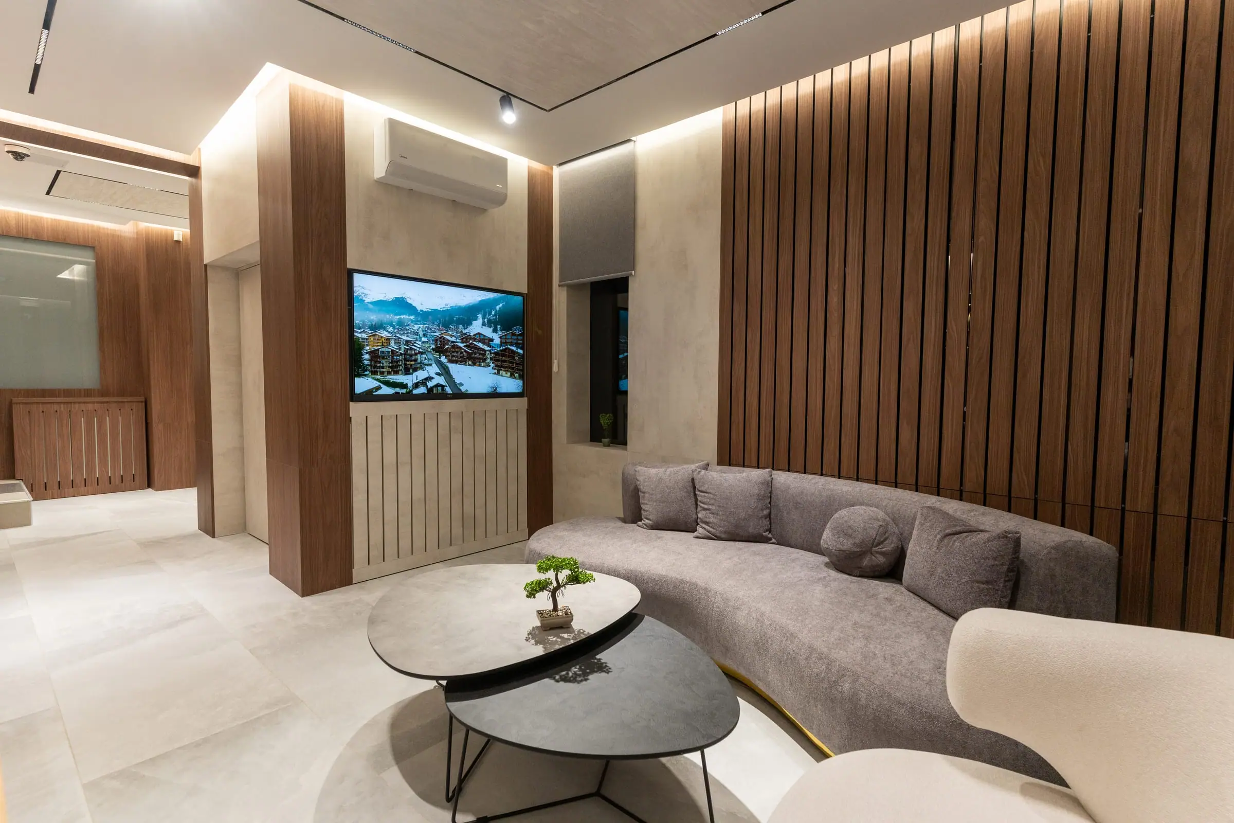 Waiting area with a sofa, coffee tables and a wall-mounted TV