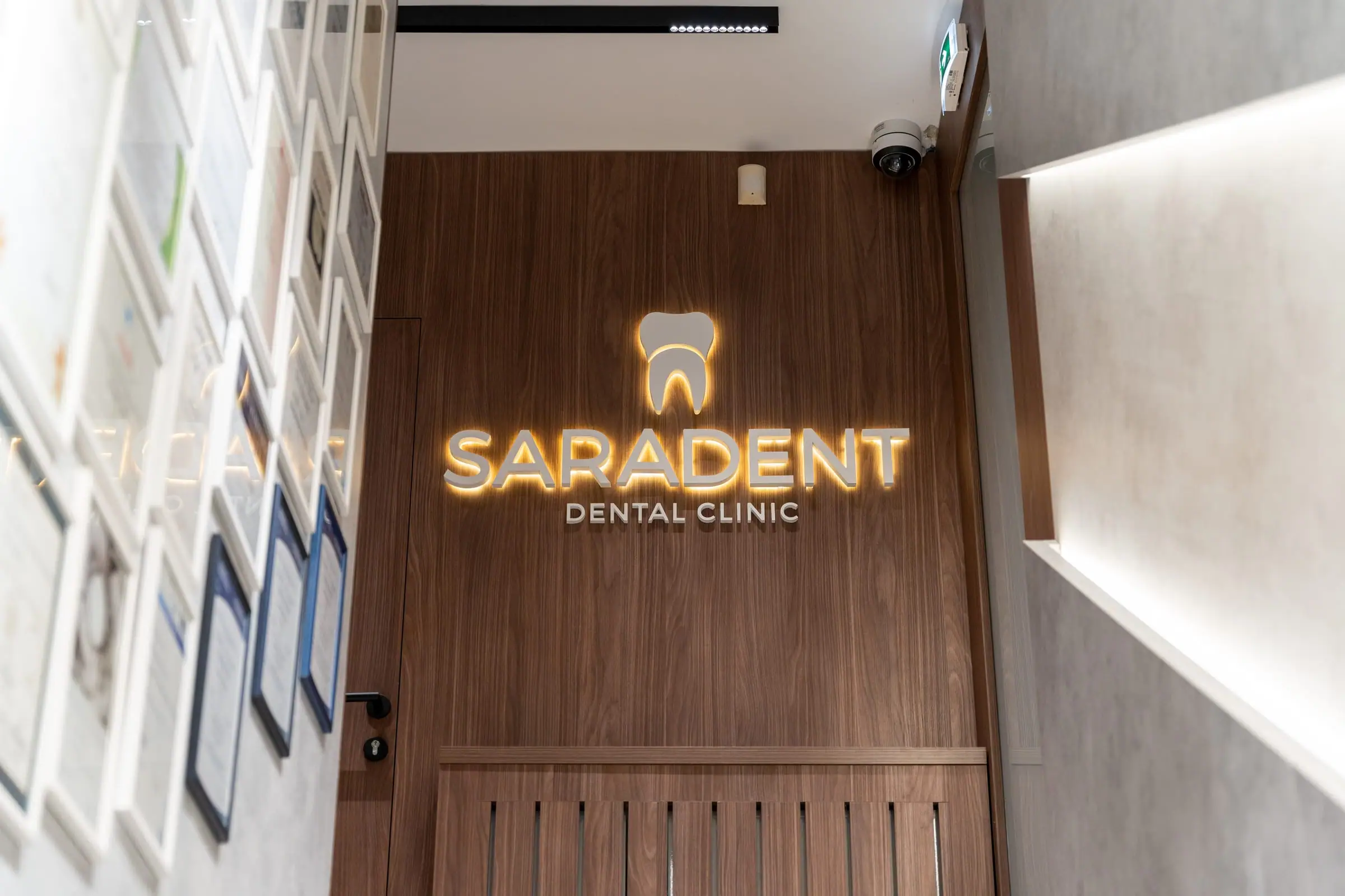 Corridor with diplomas and the illuminated logo on a walnut wall