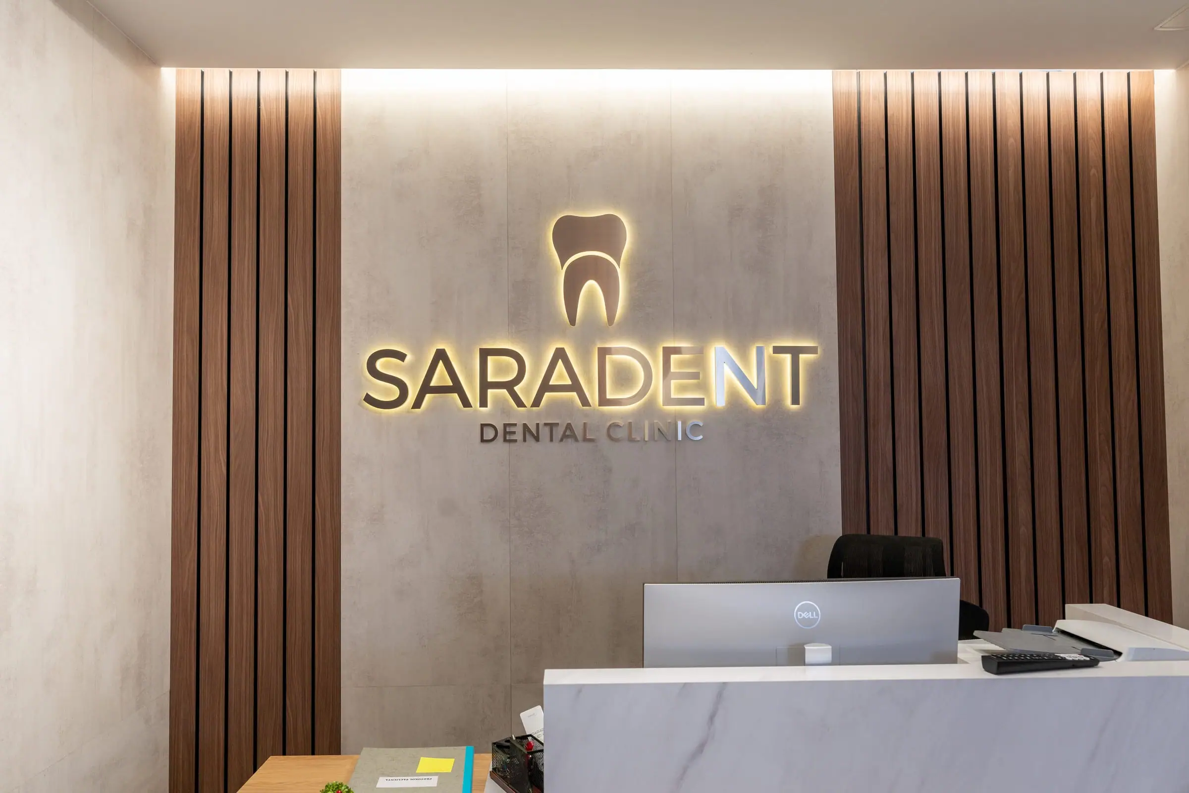 Marble reception desk in front of the wall with the gold Saradent sign